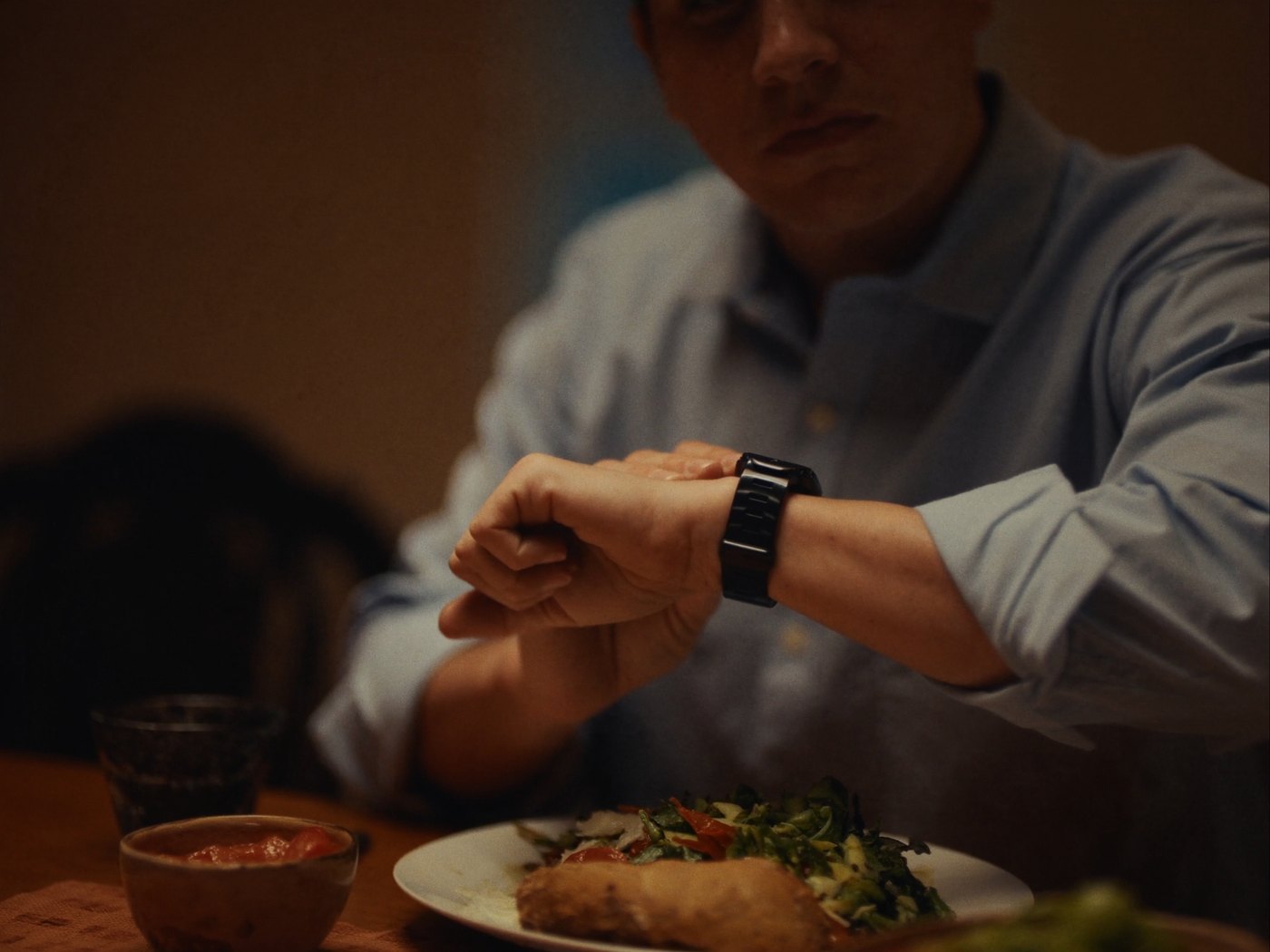 Man at the dinner table checking his Apple Watch before a meal