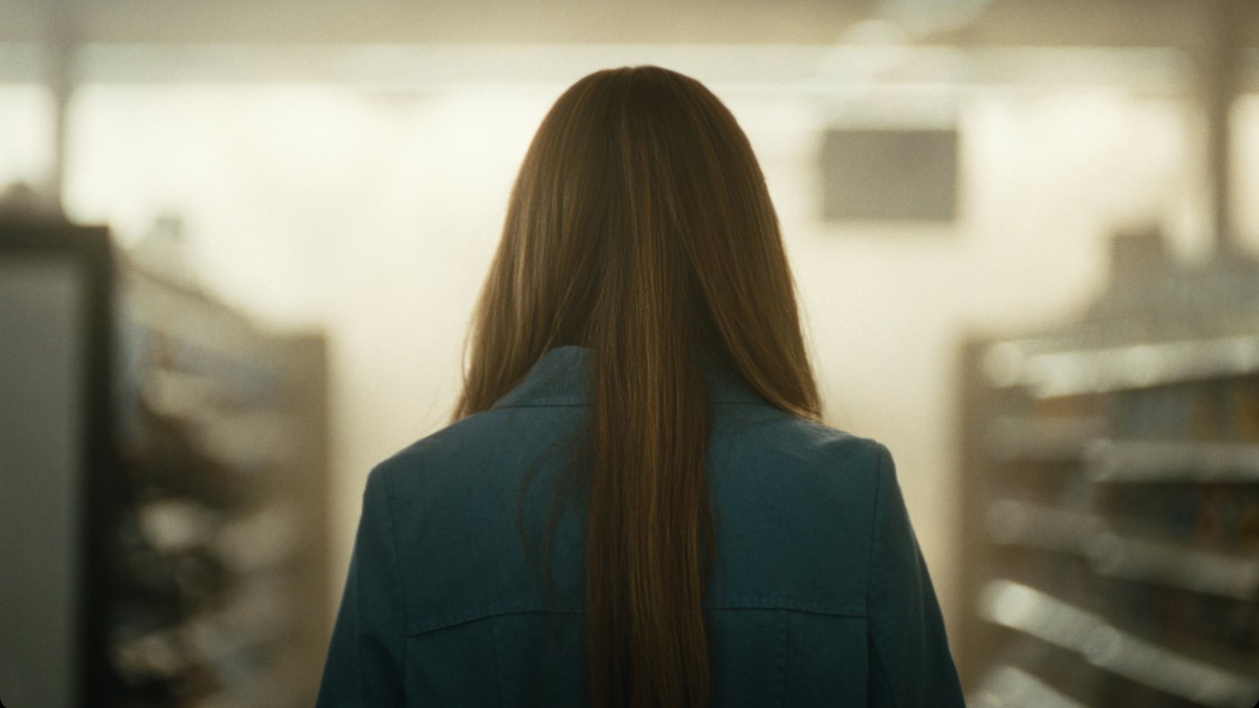 A person walking through a sunlit grocery store aisle