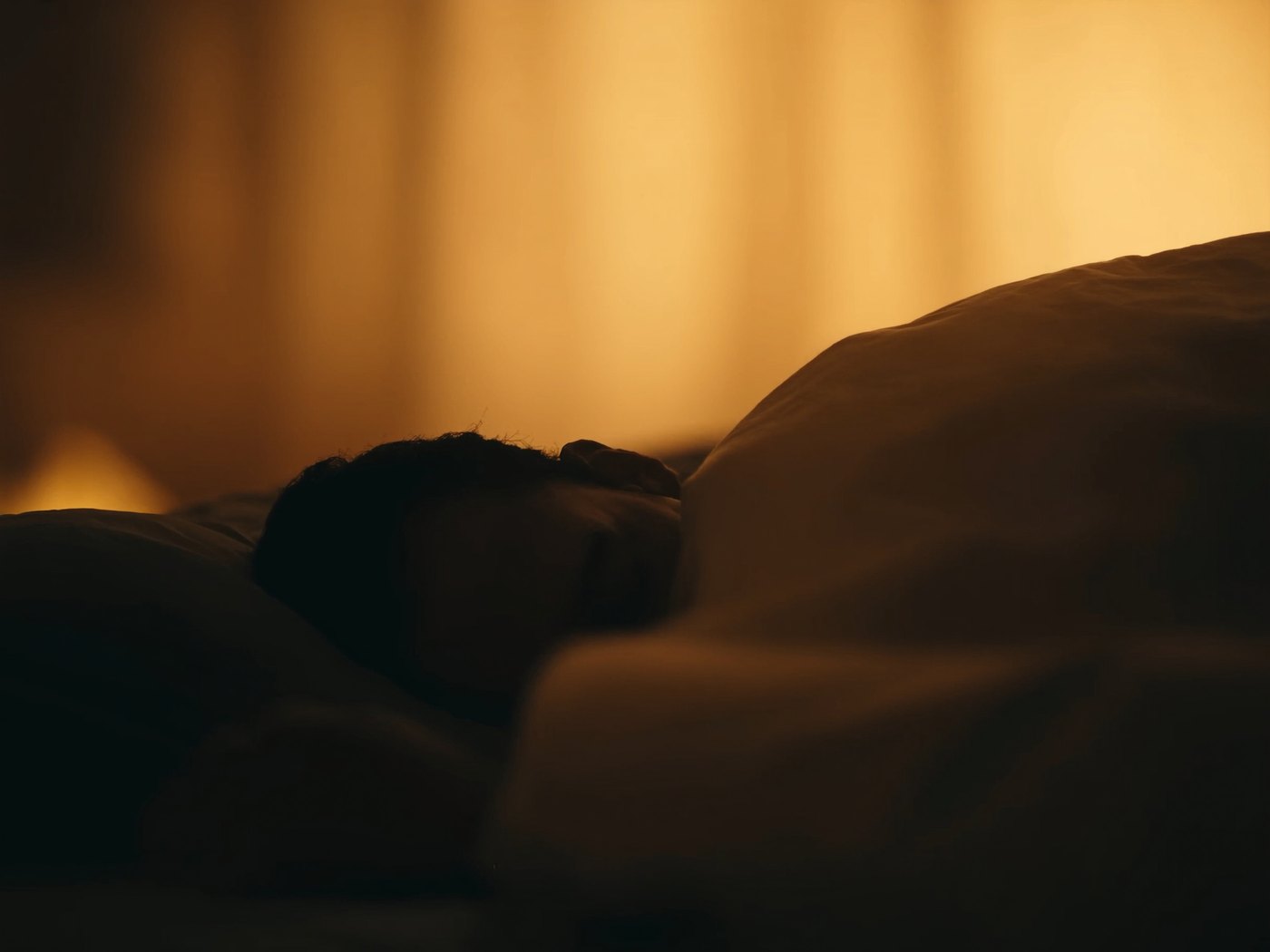 Silhouette of a person asleep as the bedroom settles into night
