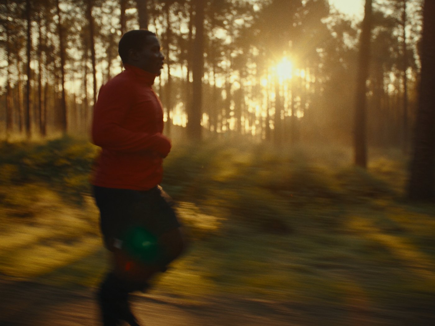 Runner mid stride on a forest trail in warm golden hour light