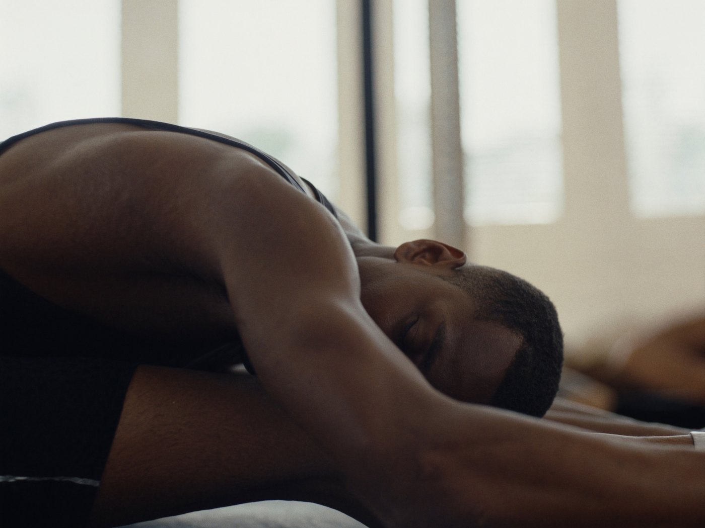 Athlete stretching and cooling down after a workout in soft natural light