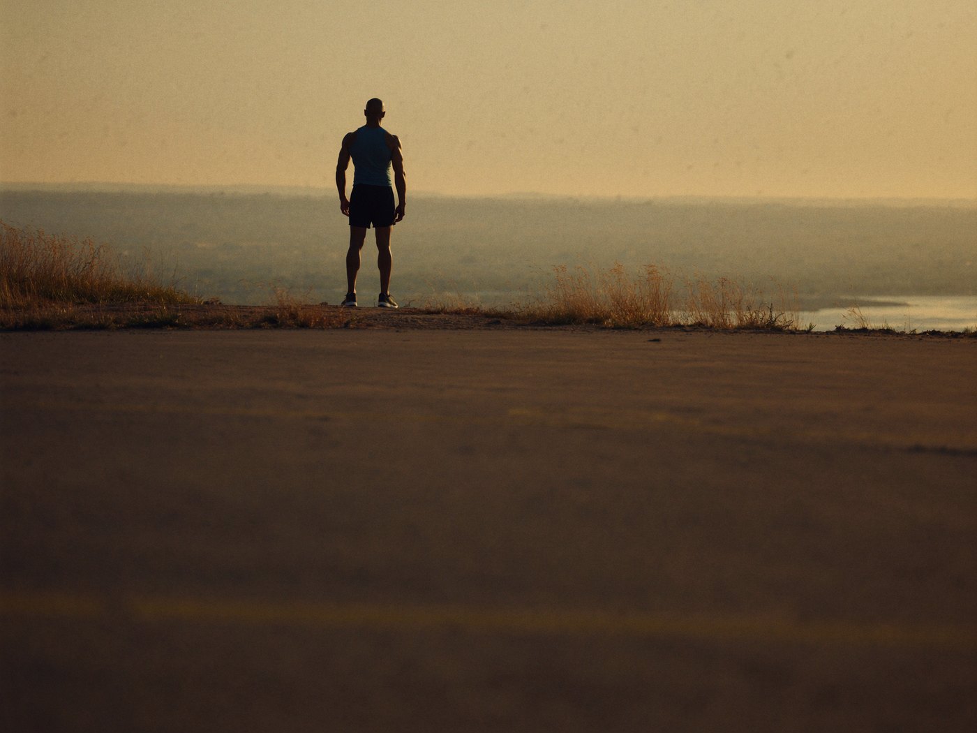 Athlete standing on a hilltop at sunrise after a workout looking over the view